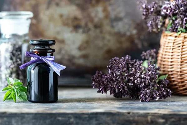 Frasco de óleo essencial de lavanda ao lado de flores frescas de lavanda roxa em um ambiente relaxante